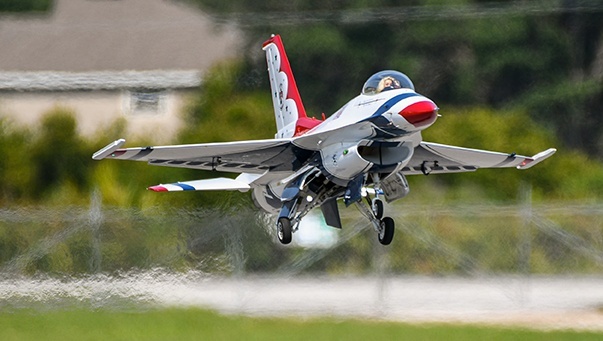 F-16 Fighting Falcons fly overhead as female vocalists from each